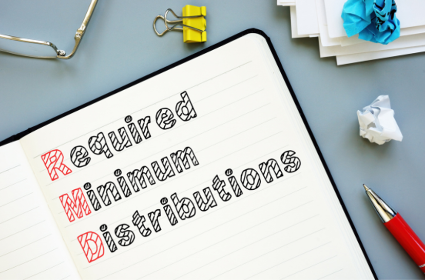 An open notebook on a gray desk with "Required Minimum Distributions" written in block letters, with the "RMD" acronym highlighted in red.